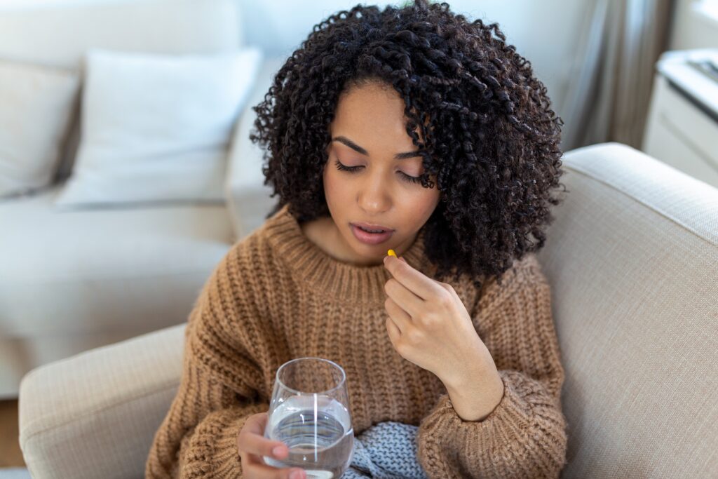 Woman holding a glass of water and preparing to take a birth control pill